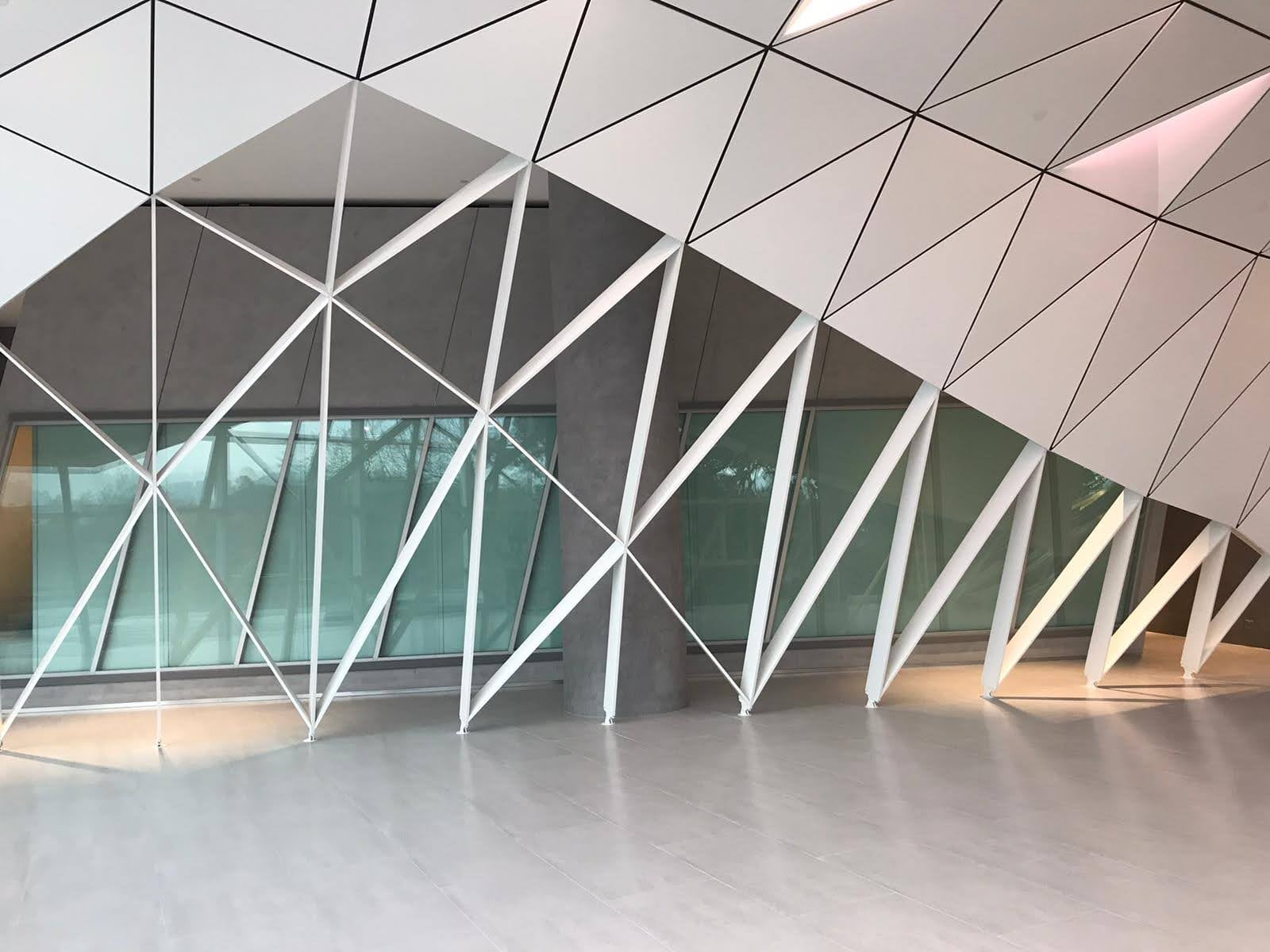 Completed glazed circulation space framed by diagonal white structural members