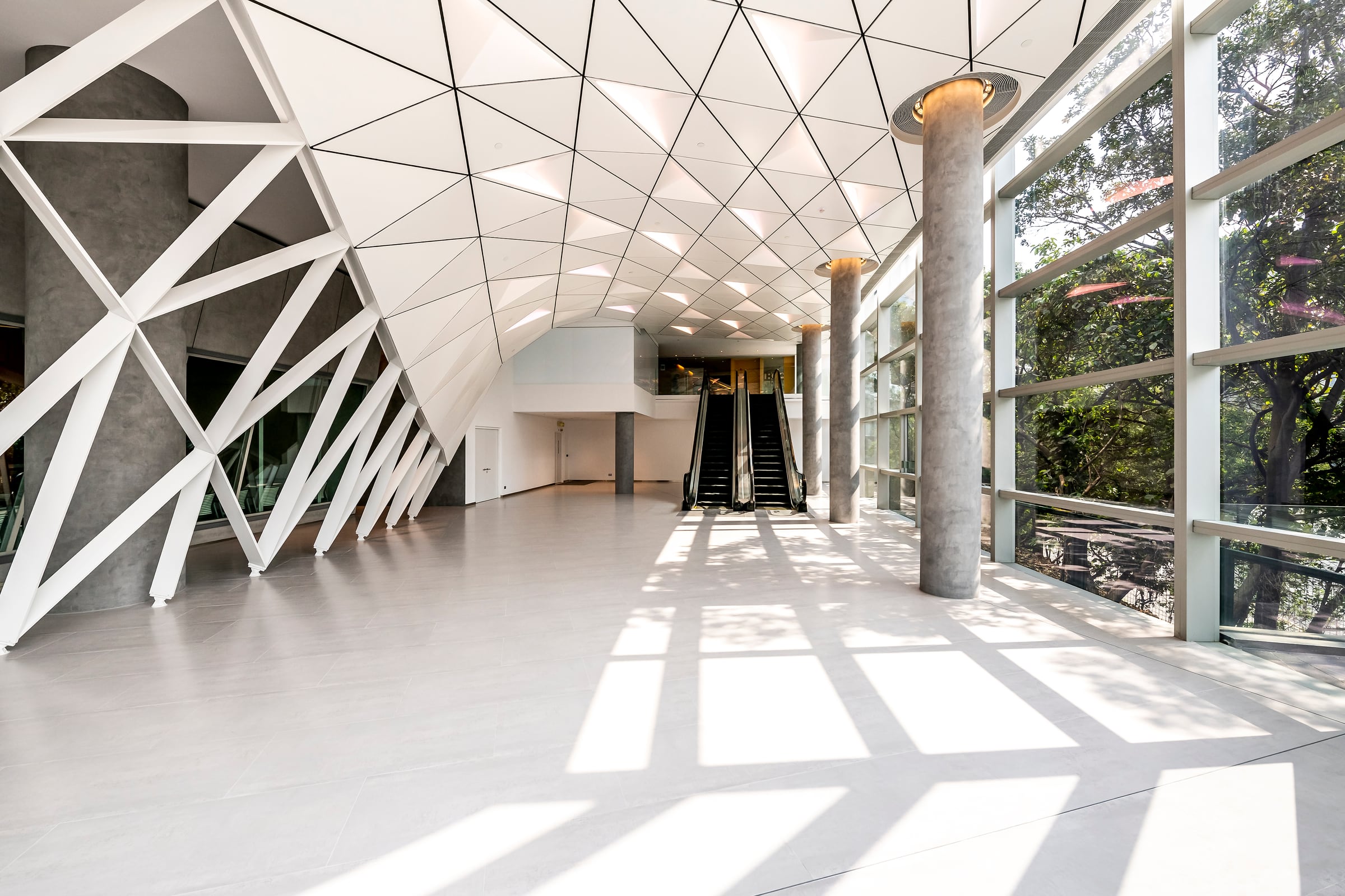 Completed glazed circulation space framed by diagonal white structural members